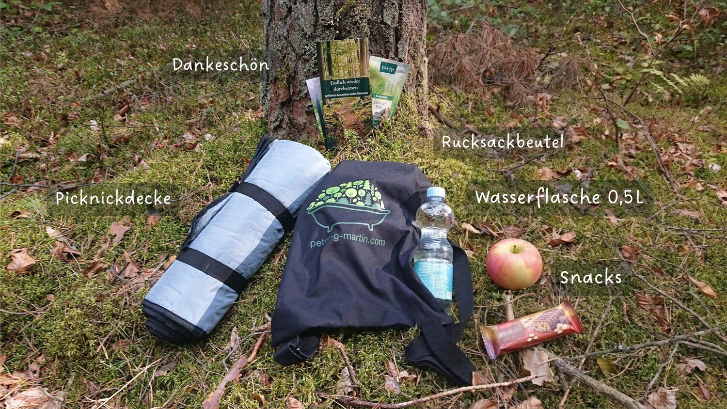 Ein Rucksackbeutel mit Picknickdecke, gefüllter Wasserflasche, Snacks und einem kleinen Dankeschön im Wald