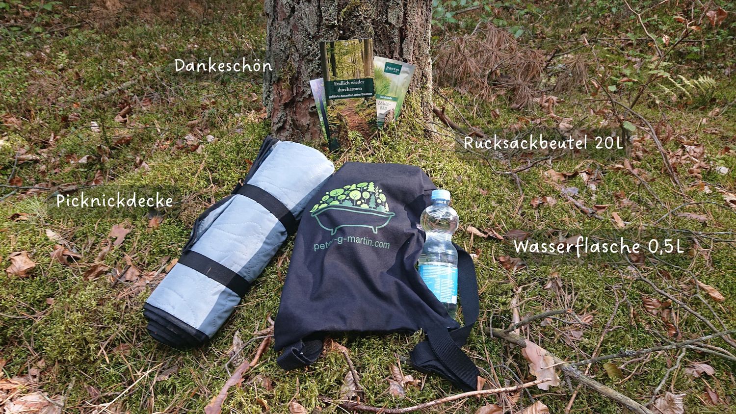 Ein Rucksack mit Picknickdecke, gefüllter Wasserflasche und einem kleinen Dankeschön-Beutel im Wald
